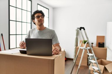 Genç İspanyol adam yeni evinde dizüstü bilgisayar kullanarak ekonomiyi hesaplıyor..