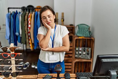 Beautiful middle age hispanic woman working as manager at retail boutique thinking looking tired and bored with depression problems with crossed arms. 