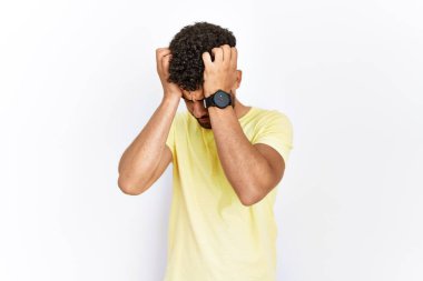 Arap genç bir adam, acı ve migren yüzünden çaresiz ve stresli bir baş ağrısından dolayı izole edilmiş arka planda duruyor. Eller başının üstünde.. 