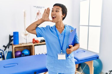 Kısa saçlı, İspanyol bir kadın ağrı kesici kliniğinde çalışıyor. Eli ağızda bağırıyor, bağırıyor. iletişim konsepti. 