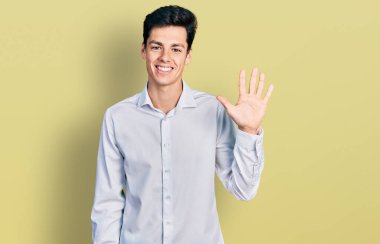 Young hispanic business man wearing business clothes showing and pointing up with fingers number five while smiling confident and happy. 