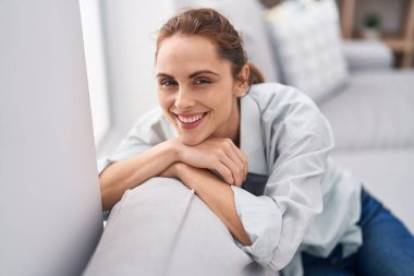 Evdeki koltukta kendinden emin gülümseyen genç bir kadın.