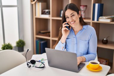 Evde çalışan akıllı telefondan konuşan genç bir kadın.