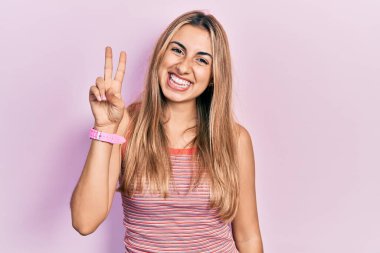 Gündelik tişört giyen güzel İspanyol kadın iki numarayı gösterip işaret ederken kendinden emin ve mutlu gülümsüyor.. 