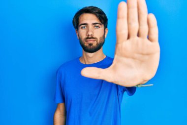 Günlük kıyafetler giyen genç İspanyol adam avucunun içi gibi şarkı söylemeyi kesiyor. Yüzünde olumsuz ve ciddi bir jest olan uyarı ifadesi. 