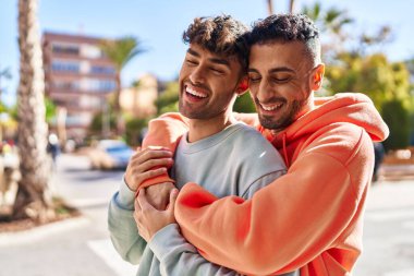 İki erkek caddede birbirlerine sarılıyorlar.