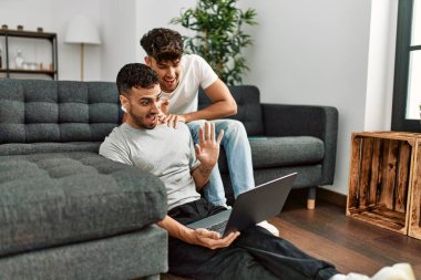İki İspanyol erkek birbirlerine sarılıyorlar ve evde video görüşmesi yapıyorlar.