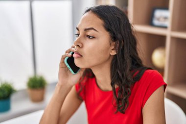 Genç Afro-Amerikan kadın akıllı telefonuyla konuşuyor. Evde ciddi bir ifadeyle.