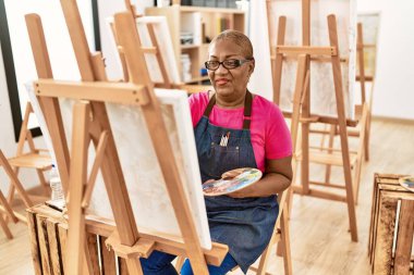 Kıdemli Afro-Amerikan kadın sanat stüdyosunda kendine güvenen çizimler yapıyor.