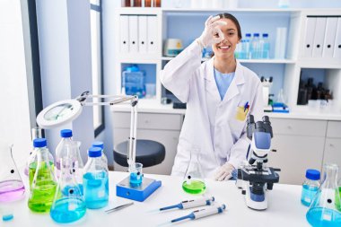 Laboratuvarda çalışan esmer bir kadın gülümsüyor. Mutluluktan gülümsüyor. 