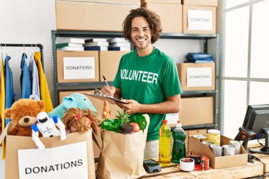 Yardım derneğindeki panoya mutlu yazılar yazarak gülümseyen genç İspanyol gönüllü adam..