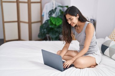 Yatak odasında dizüstü bilgisayar kullanan genç İspanyol kız.