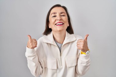 Orta yaşlı İspanyol kadın izole edilmiş arka plan başarı işaretinin başında duruyor. Elleriyle olumlu jest yapıyor, gülümsüyor ve mutlu. Neşeli ifade ve kazanan jest. 