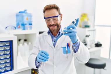 Orta yaşlı, labaratuarda çalışan bilim adamı üniforması giyen bir İspanyol.