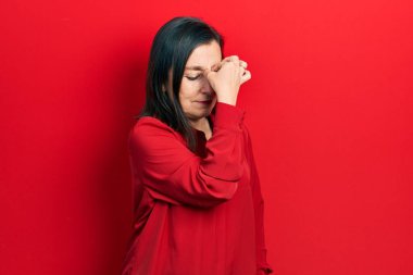 Orta yaşlı İspanyol kadın gündelik kıyafetler giyip yorgun burnu ve gözleri ovuşturup yorgunluk ve baş ağrısı çekiyor. Stres ve hüsran kavramı. 