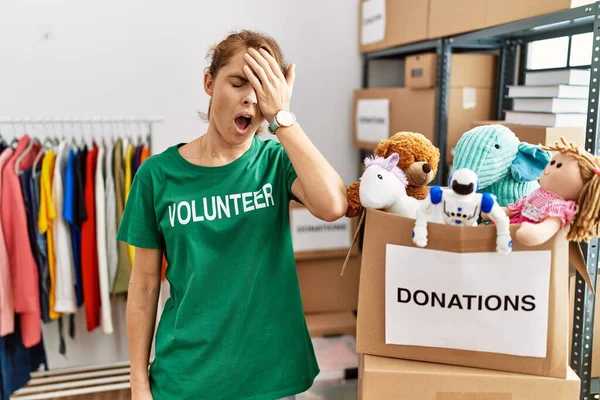 Beautiful caucasian woman wearing volunteer t shirt at donations stand yawning tired covering half face, eye and mouth with hand. face hurts in pain. 