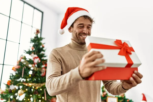 Joven Hombre Hispano Sonriendo Confiado Sosteniendo Regalo Navidad Casa —  Fotos de Stock