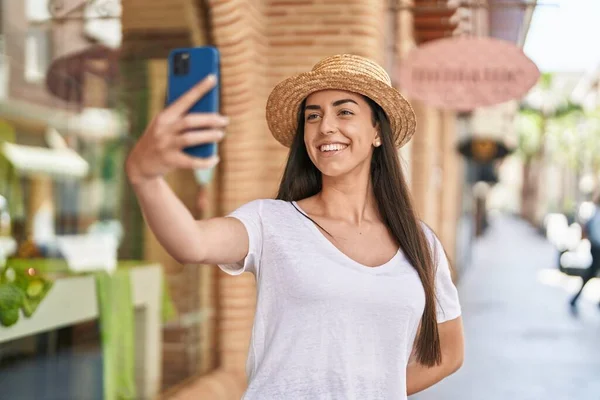 Young hispanic woman tourist smiling confident making selfie by the smartphone at street