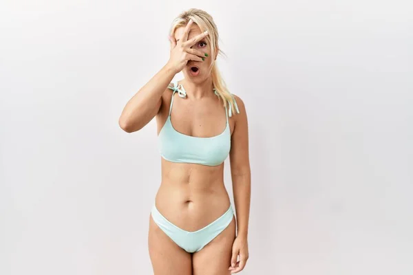 Young Caucasian Woman Wearing Bikini Isolated Background Peeking Shock Covering — Stok fotoğraf