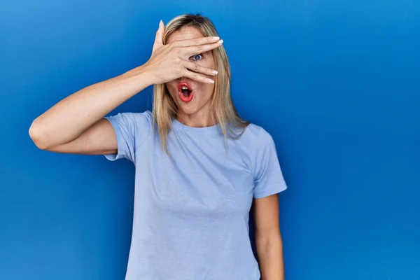 Beautiful Blonde Woman Wearing Casual Shirt Blue Background Peeking Shock — Stockfoto