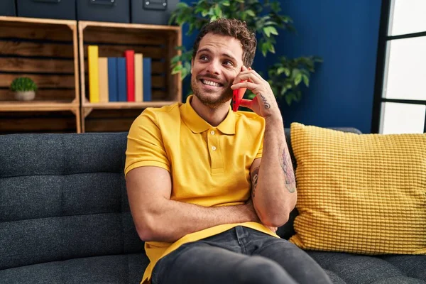 Young Hispanic Man Talking Smartphone Sitting Sofa Home — Stockfoto