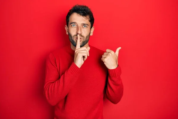 Przystojny Mężczyzna Brodą Czerwonym Swetrze Proszący Ciszę Palcem Ustach Skierowanym — Zdjęcie stockowe