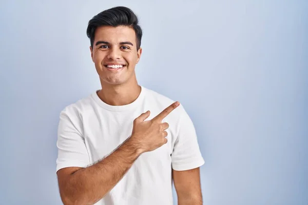 Homem Hispânico Sobre Fundo Azul Alegre Com Sorriso Rosto Apontando — Fotografia de Stock
