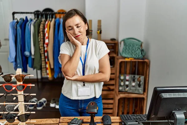Beautiful middle age hispanic woman working as manager at retail boutique thinking looking tired and bored with depression problems with crossed arms. 