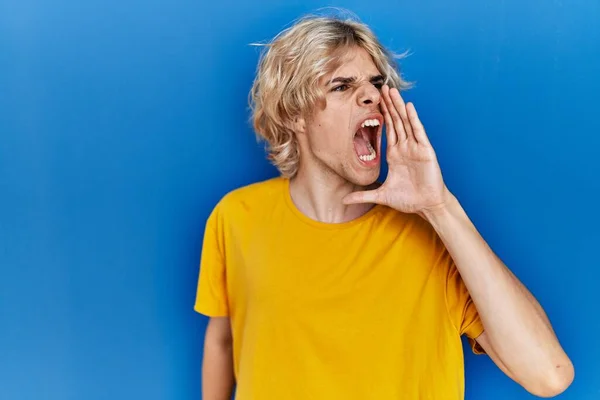 Mladý Moderní Muž Stojící Nad Modrým Pozadím Křičící Křičící Stranu — Stock fotografie