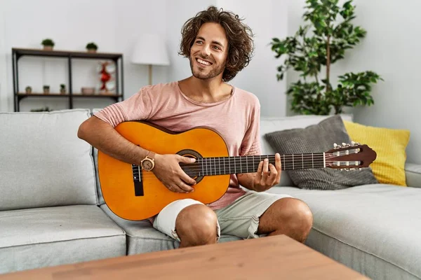Joven Hombre Hispano Sonriendo Feliz Tocando Guitarra Clásica Sentado Sofá — Foto de Stock