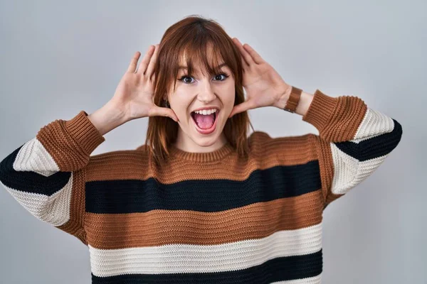 İzole edilmiş arka planda çizgili süveter giyen genç ve güzel bir kadın. Gülümseyen, güler yüzlü, ellerini gösteren bir yuhalama bakıyor. Şaşırdım ve çıktım. 