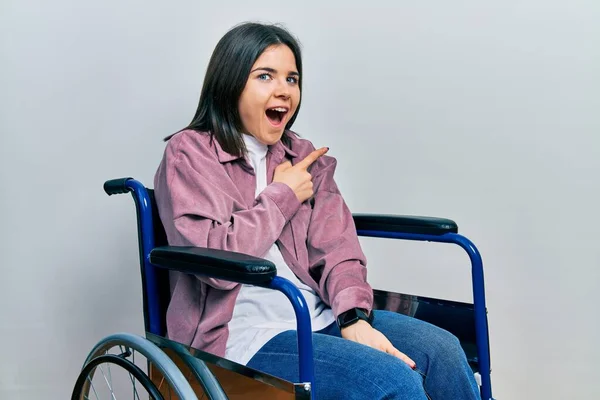 Молода Брюнетка Сидячи Інвалідному Візку Здивована Вказуючи Пальцем Бік Відкритий — стокове фото