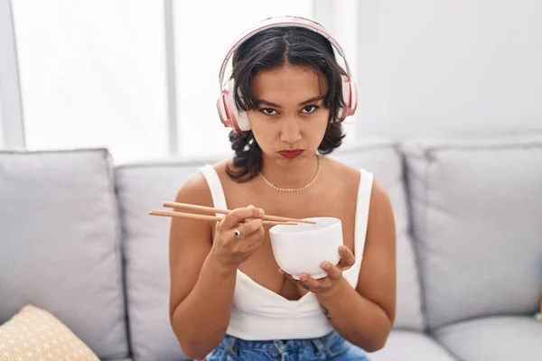 年轻的惊慌失措的女人用筷子吃着亚洲菜 疑神疑鬼 神经紧张 皱着眉头因为问题而心烦意乱 消极的人 — 图库照片