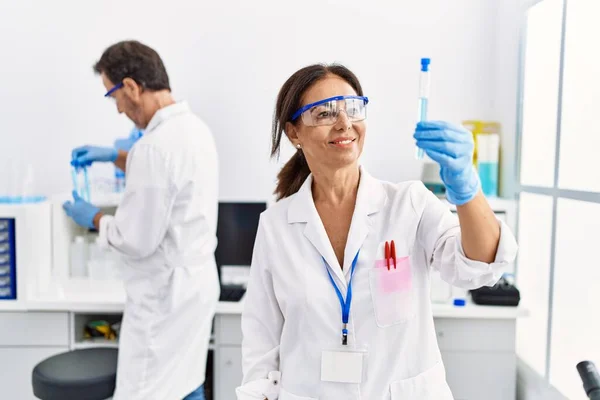 中年男人和女人穿着科学家制服在实验室拿着试管 — 图库照片