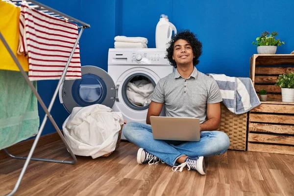 在洗衣房用笔记本电脑等洗衣机的年轻人 — 图库照片