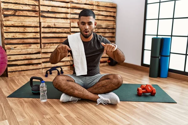 Young Indian Man Sitting Training Mat Gym Pointing Fingers Showing — Stockfoto