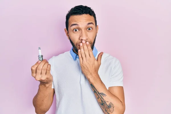 Hispanic Man Beard Holding Spark Plug Covering Mouth Hand Shocked — Stock fotografie