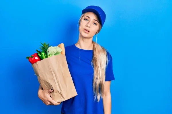 Junge Kaukasische Frau Kurieruniform Mit Lebensmitteln Aus Dem Supermarkt Sieht — Stockfoto