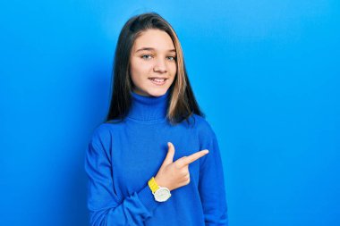 Young brunette girl wearing turtleneck sweater cheerful with a smile on face pointing with hand and finger up to the side with happy and natural expression 