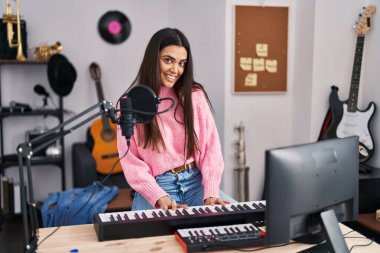 Genç İspanyol kadın müzisyen müzik stüdyosunda piyano klavyesi çalıyor.