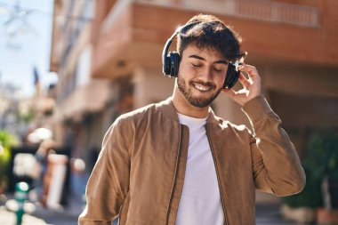 Sokakta müzik dinlerken kendinden emin gülümseyen İspanyol genç adam.