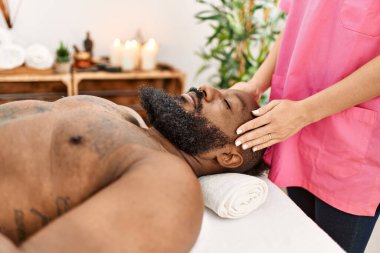 Genç Afrikalı Amerikalı adam güzellik merkezinde kafa masajı yaptırıyor.