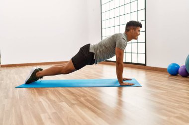 Genç İspanyol adam gülümsüyor spor merkezinde esniyor.