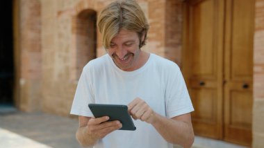 Sokakta dokunmatik ped kullanan, kendine güvenen genç sarışın adam.