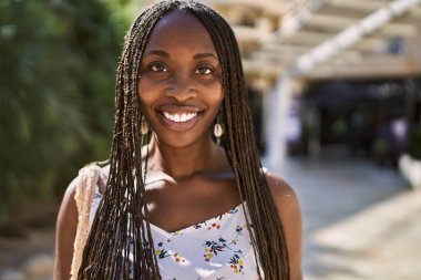 Genç Afrikalı Amerikalı kadın gülümseyerek şehirde mutlu mesut duruyor..