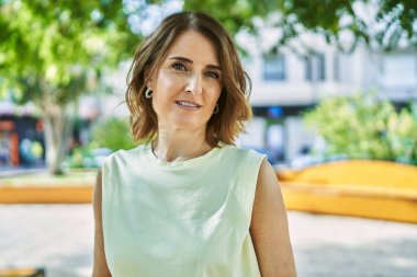 Orta yaşlı bir kadın şehirde mutlu mesut ayakta duruyor..