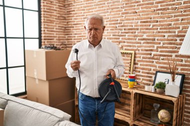 Senior man with grey hair holding extension plug depressed and worry for distress, crying angry and afraid. sad expression. 