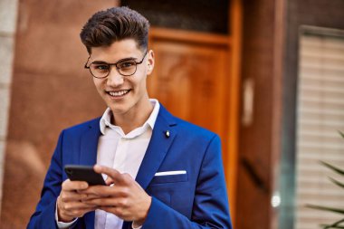 Sokakta takım elbise ve gözlük takan akıllı telefon kullanan genç adam.
