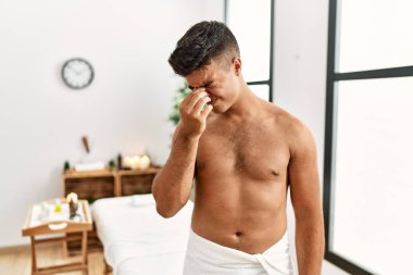 İspanyol asıllı genç adam kaplıca merkezinde üstsüz duruyor. Burnu ve gözleri ovuşturup yorgunluk ve baş ağrısı çekiyor. Stres ve hüsran kavramı. 