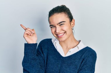 Yüzünde kocaman bir gülümseme olan, el ve parmak ile kameraya bakan, günlük kıyafetler giyen genç beyaz bir kız.. 